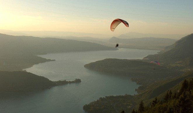 Parapente au dessus du lac d'Annecy au coucher de soleil - © Savoie Mont Blanc / Zvardon